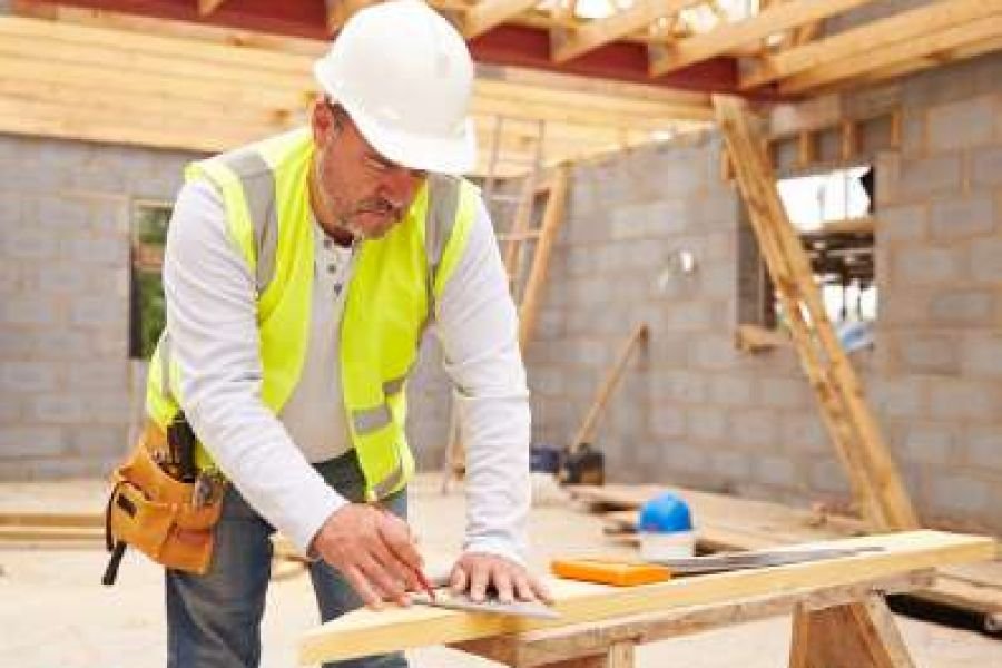 Carpenter measuring and marking timber on a building site
