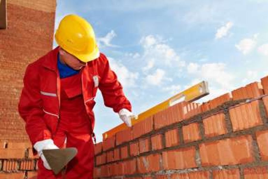 Mason laying brickwork with a spirit level on a construction project