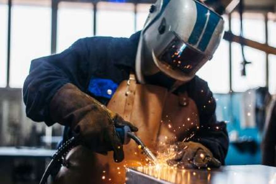 Certified welder working with sparks in a fabrication workshop